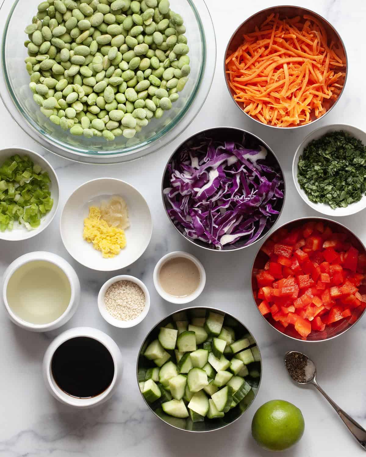 Ingredients including edamame, cabbage, carrots, scallions, cucumbers, tahini, ginger, garlic, cilantro and oil.