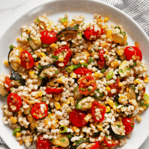 Dressed in red wine vinaigrette, this easy barley salad has an entire sheet pan of roasted tomatoes, corn and zucchini stirred into the cooked grains. This is a recipe that makes multitasking so simple. You can simmer the barley and whisk together the dressing while the vegetables roast in the oven. When you assemble the salad, you also fold in sliced scallions and chopped parsley. You can serve this vegan grain salad as a side dish or a main dish.