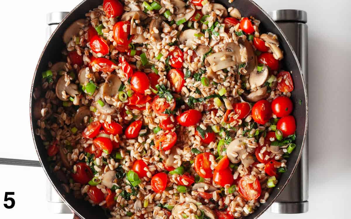 Farro with mushrooms, tomatoes and kale in the skillet.