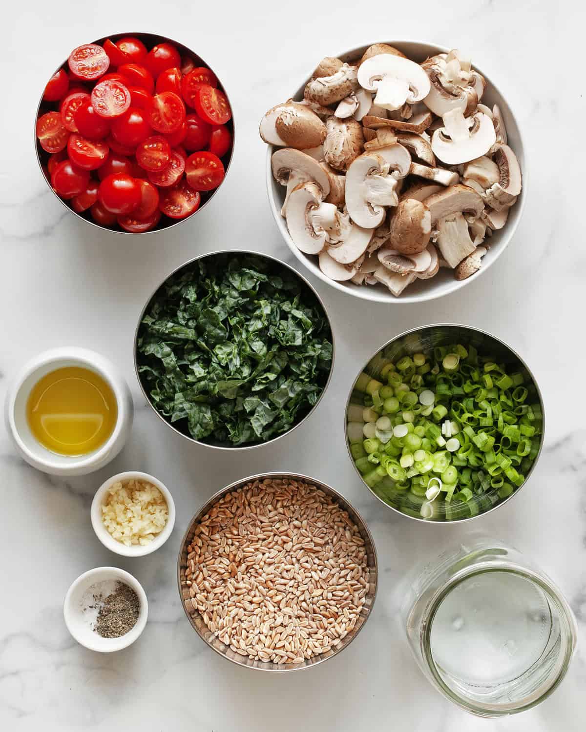 Ingredients including mushrooms, tomatoes, farro, kale, scallions, garlic, olive oil, salt and pepper.