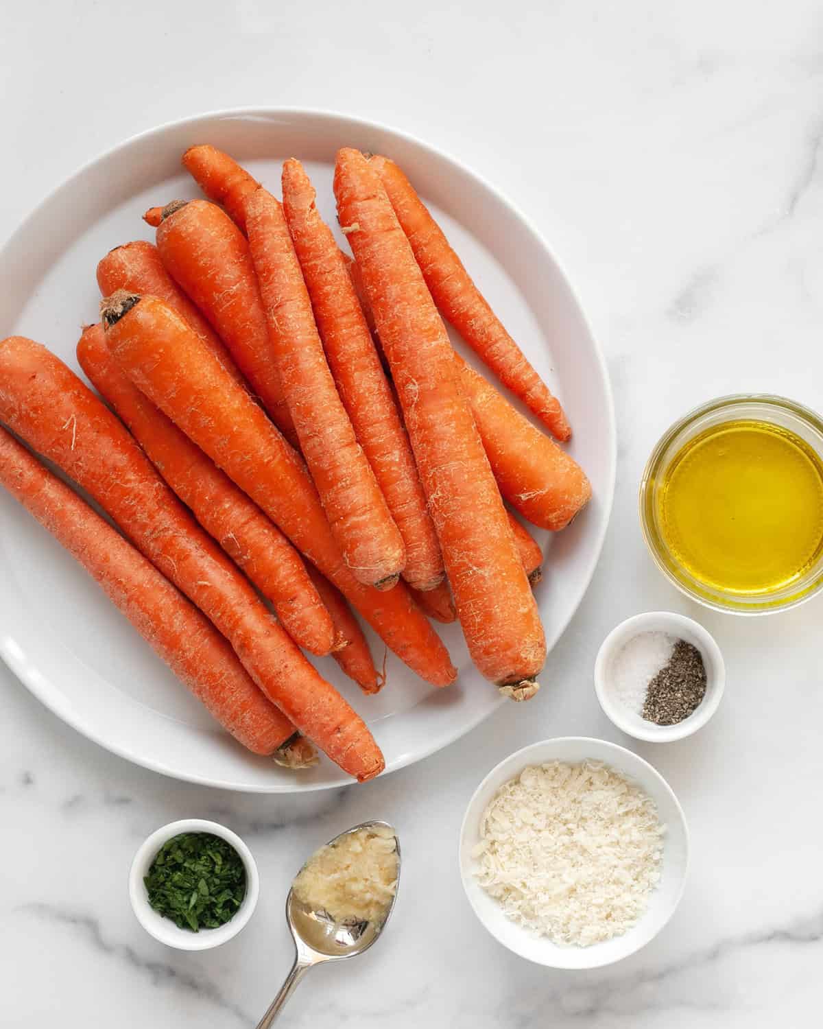 Ingredients including carrots, parmesan, garlic cloves, parsley, olive oil, salt and pepper.