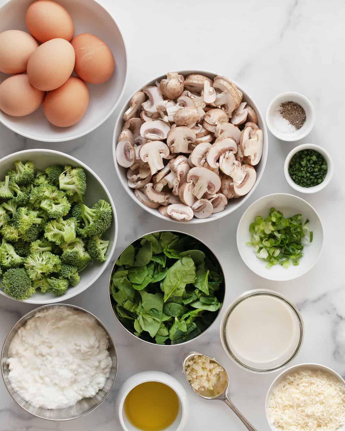 Ingredients including eggs, broccoli, mushrooms, scallions, spinach, chives, oil, salt, pepper, garlic and parmesan.