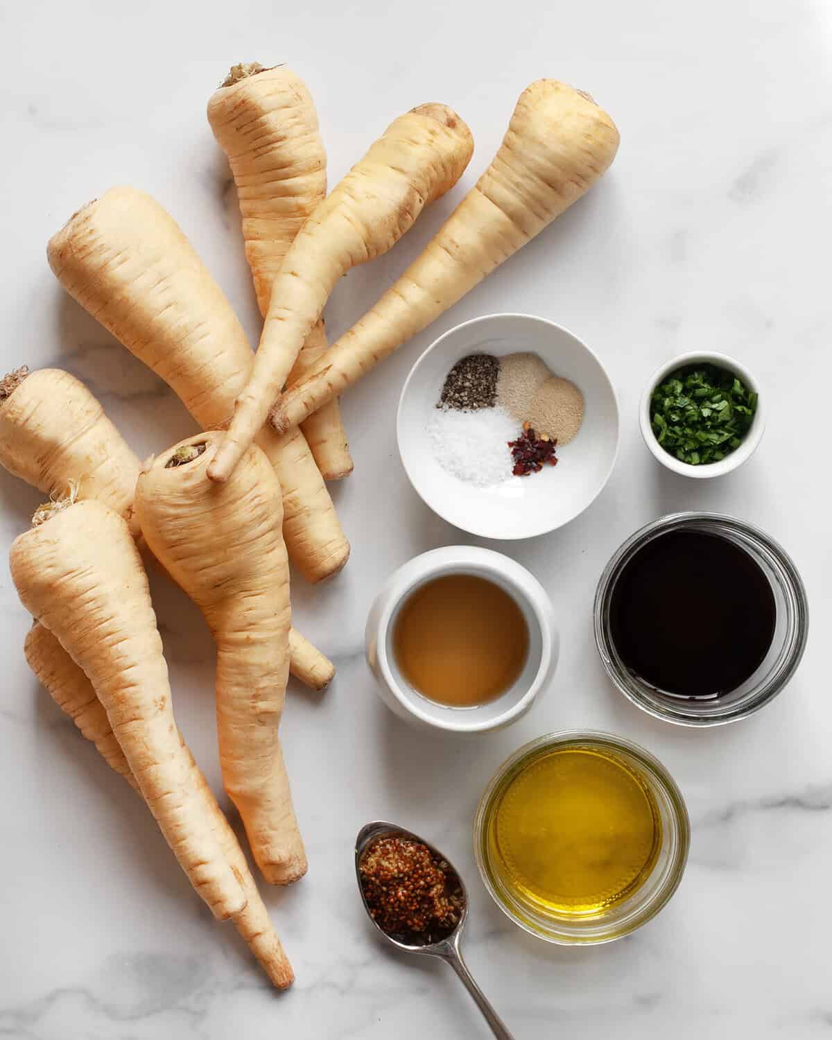 Ingredients including parsnips, maple syrup, balsamic vinegar, dried spices, olive oil and fresh herbs.