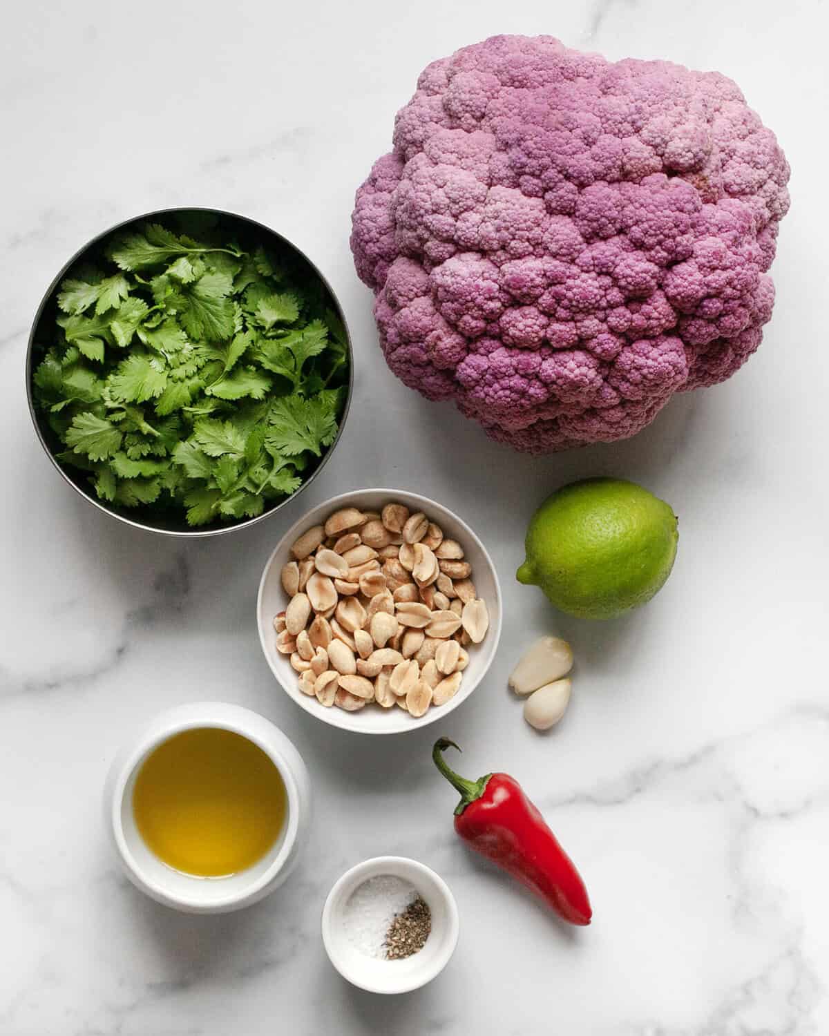 Ingredients including purple cauliflower, olive oil, salt, pepper, garlic, red chilies, lie, peanuts, cilantro and olive oil.