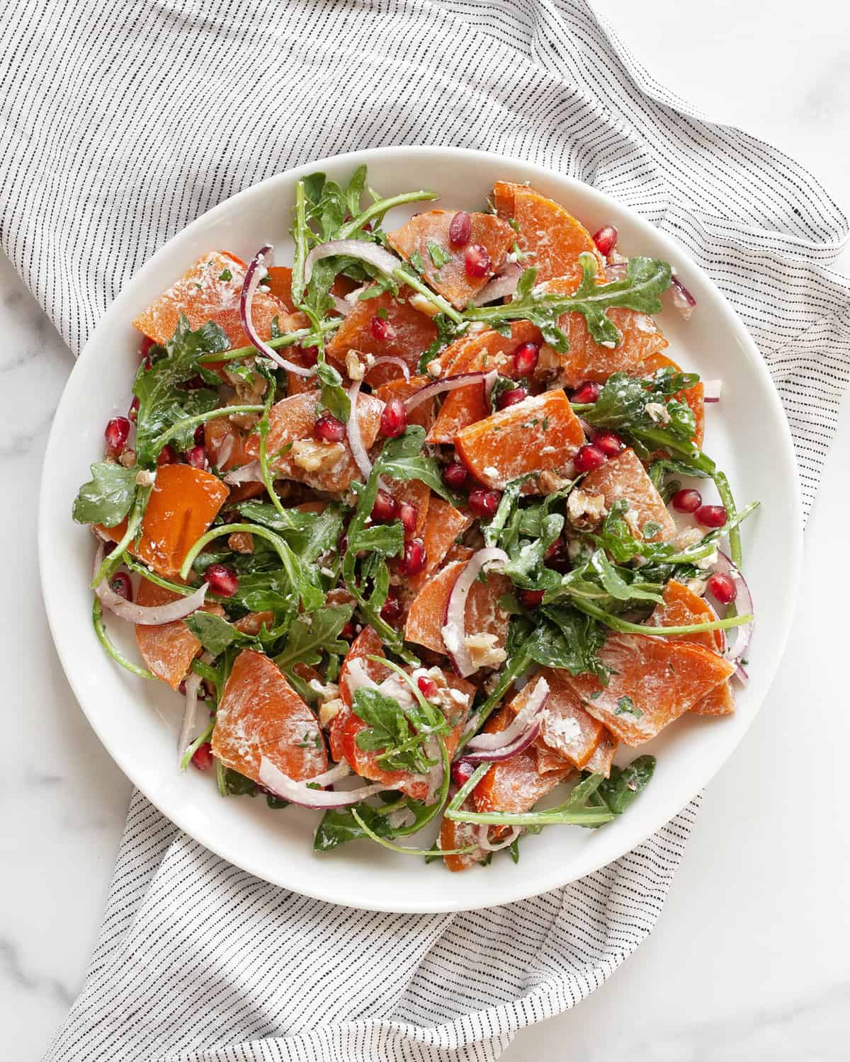 Persimmon and arugula salad on a plate.