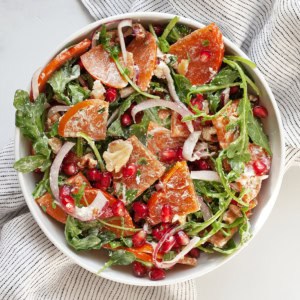 Arugula salad with persimmons in a bowl.