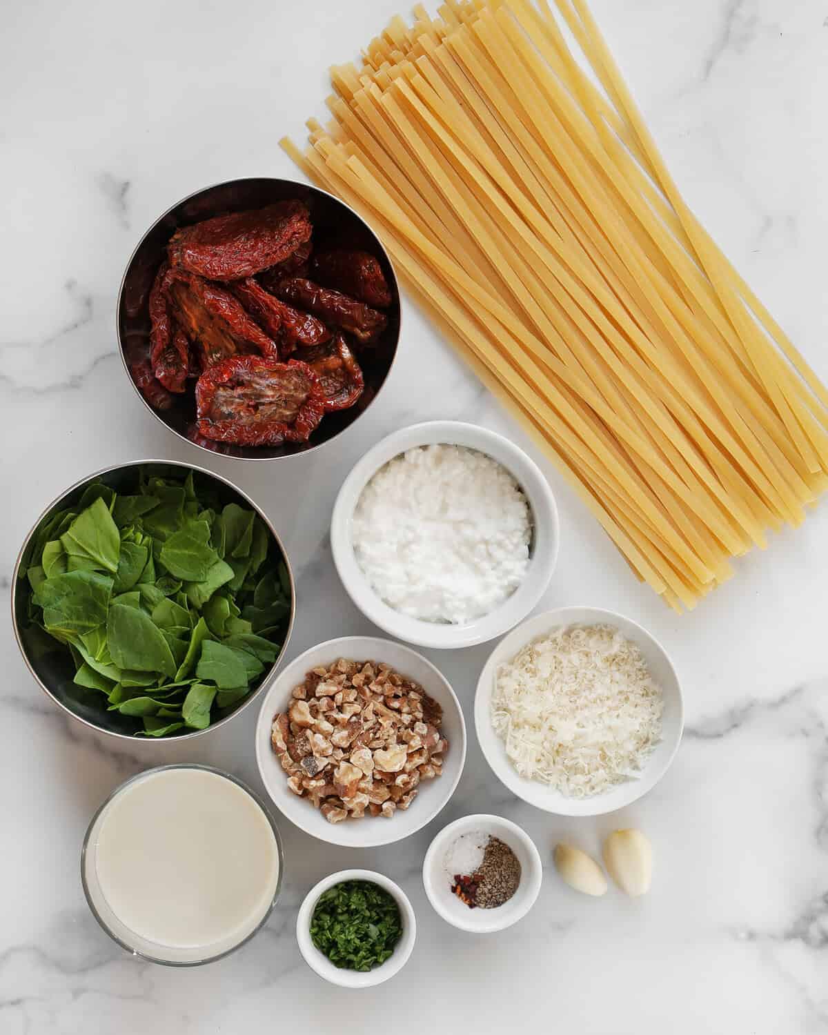 Ingredients including sun dried tomato, fettuccine, cottage cheese, garlic, parmesan, walnuts, spinach, olive oil, and parsley.