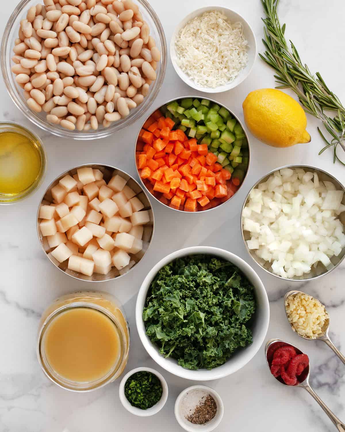 Ingredients including cannellini beans, onions, carrots, celery, garlic, rosemary, vegetable broth, olive oil, tomato paste, salt and pepper.