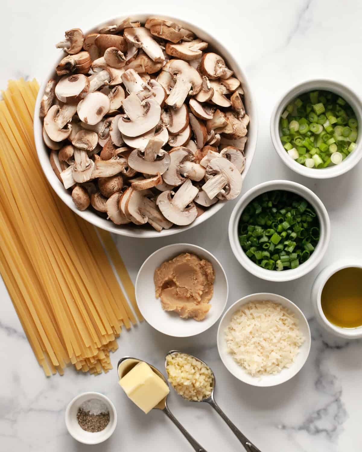 Ingredients including mushrooms, miso paste, fettuccine, scallions, parmesan, garlic, olive oil, salt and pepper.