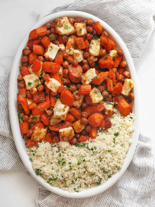 Harissa honey roasted carrots with chickpeas and halloumi with couscous on an oval serving platter.