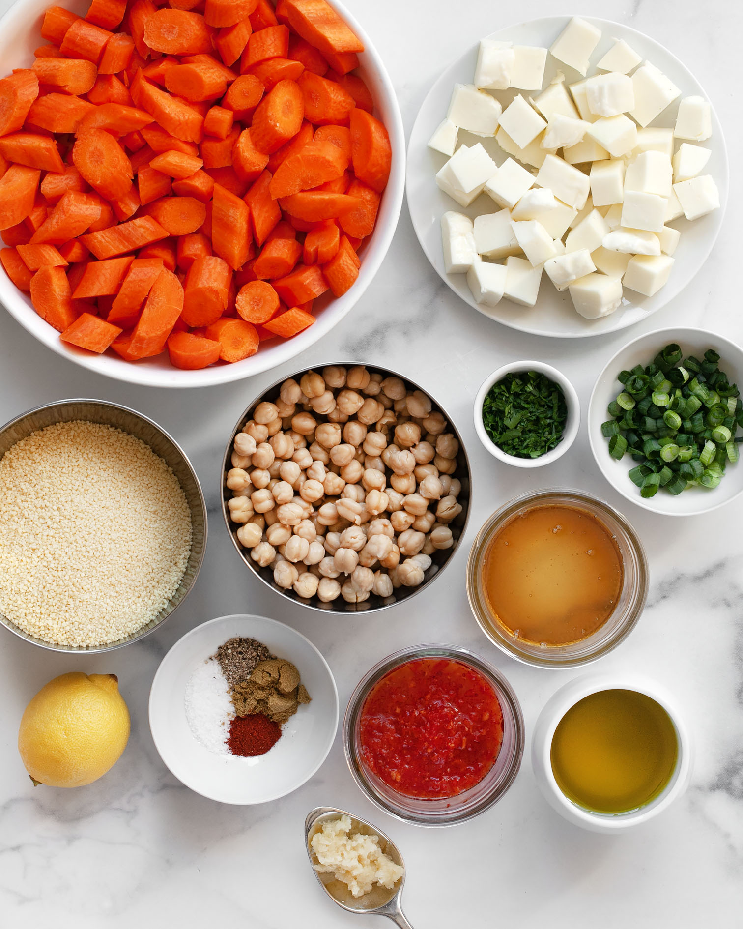 Ingredients including carrots, halloumi, chickpeas, olive oil, dried spices, honey, harissa, garlic, couscous, lemon, scallions and parsley.